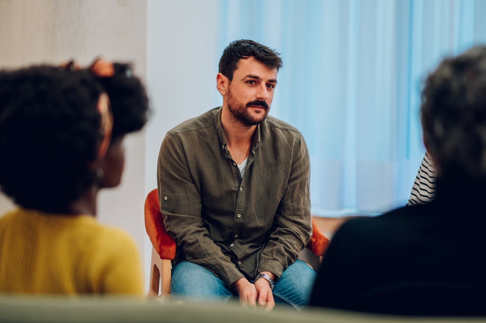 man sitting in group therapy circle for addiction counseling